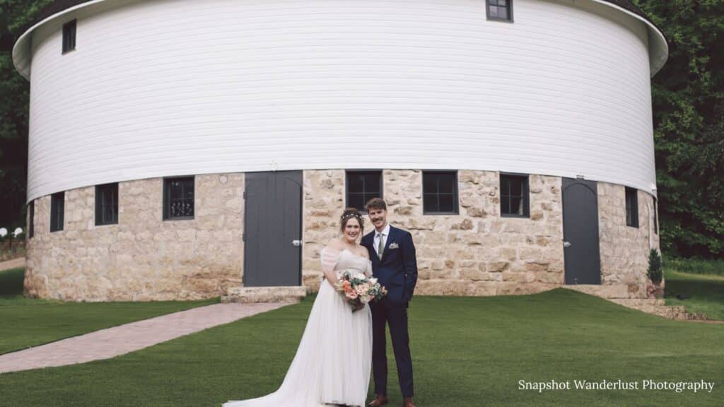 Newly married couple stands in front of the historic round barn for their wedding day photos in Red Wing, Minnesota.