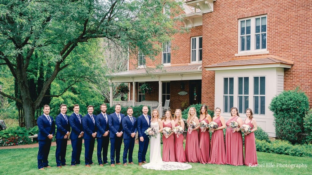 Bridal party poses for the wedding photographer in front of the Round Barn Farm Bed and Breakfast and wedding venue. Located in Red Wing, Minnesota. 