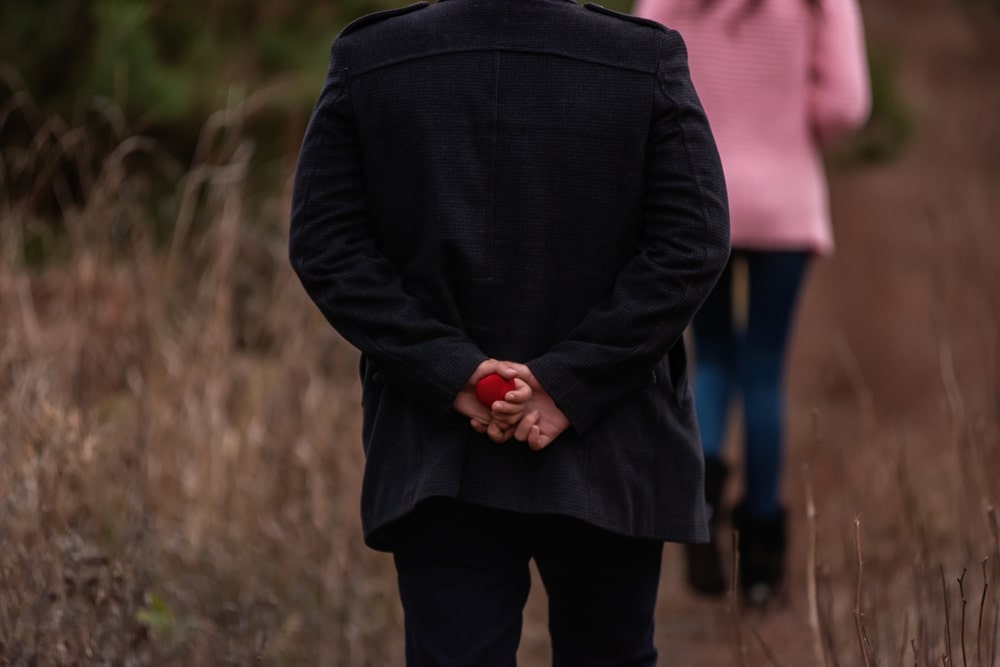 Man holding a ring behind his back on his way to propose at the top of Barn Bluff in Red Wing