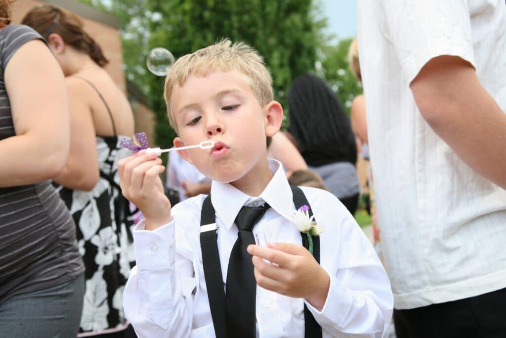 Young boy at wedding blowing bubbles. One of the best wedding exit ideas.