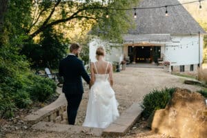 Couple walking toward historic round barn together, quiet moment after ceremony.